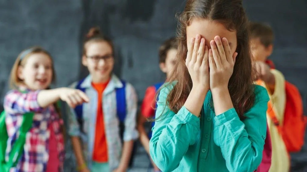 Meninos fazem bullying a uma criança que chora desconsolada.