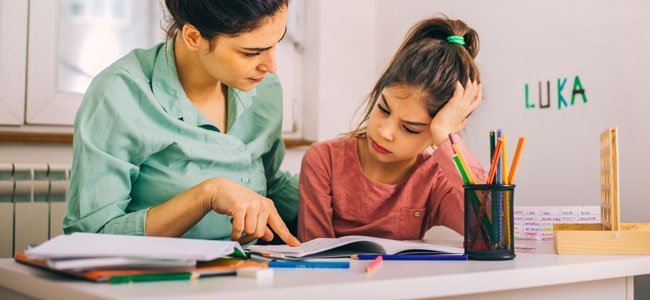 Mãe ajuda a sua filha com dificuldades de aprendizagem.