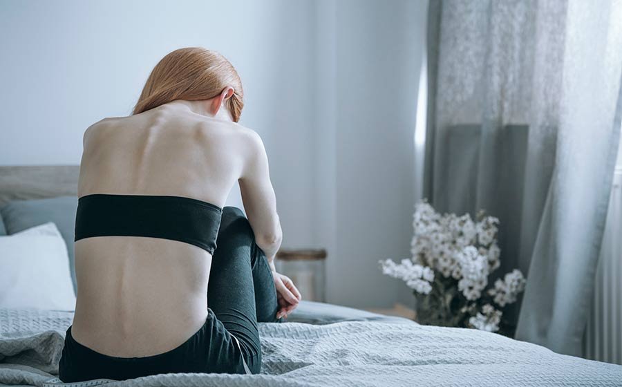 mulher com anorexia nervosa sentada na cama